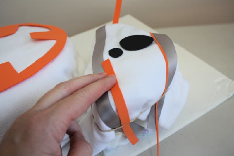 hand adding ribbon details to top of BB-8 Diaper cake