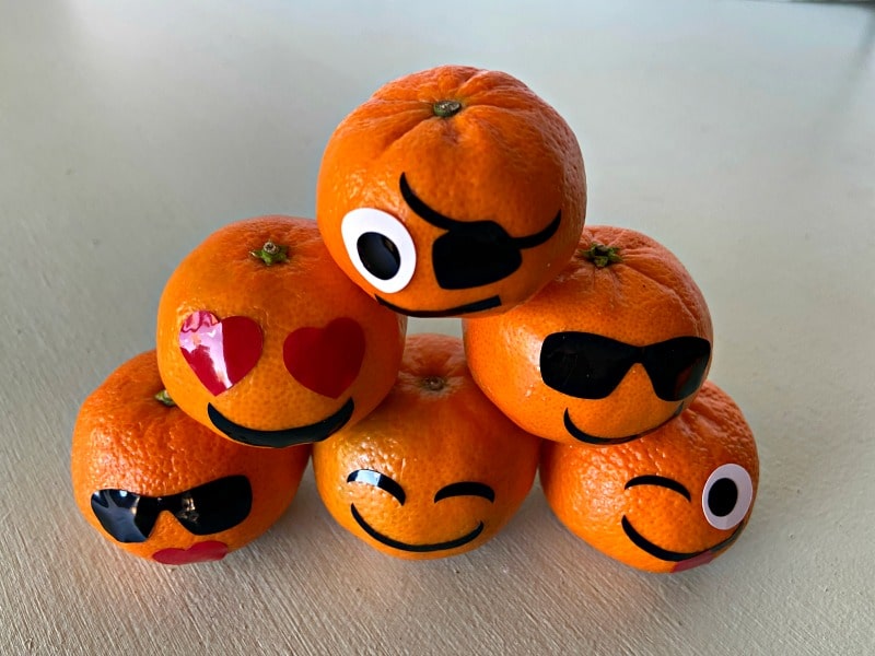 oranges decorated with emoji faces