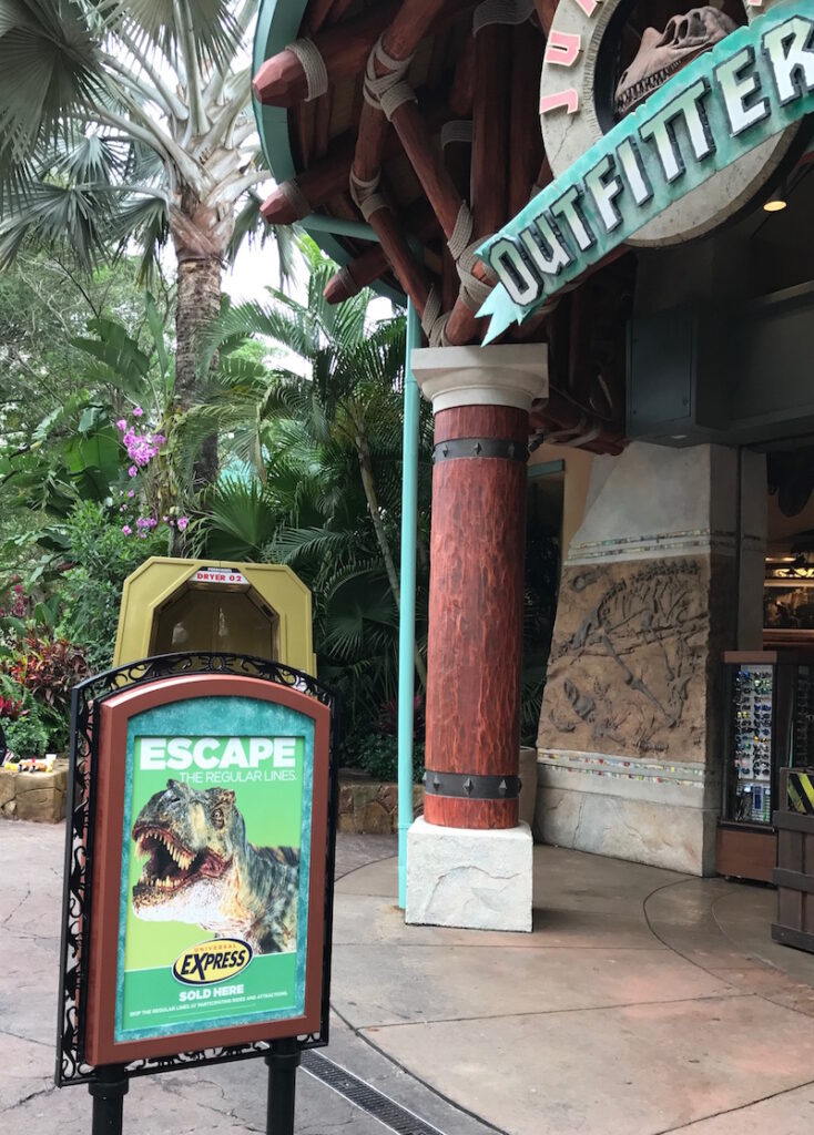 Sign with a dinosaur advertising Universal Orlando Express Pass purchase outside a gift shop