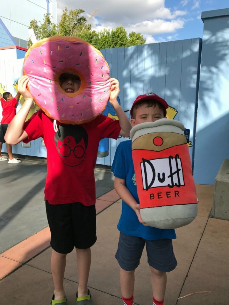Kids holding giant pink donut and Duff beer stuffed animal