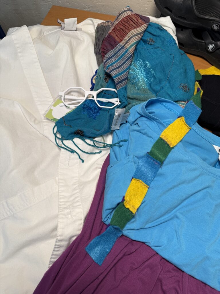 Clothing and accessories for a DIY Olivia Octavius costume, including a purple dress, blue shirt, white lab coat, glasses and felt headband.