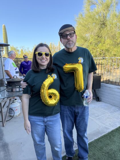 Two adults wearing DIY 6-7 Halloween costumes made with gold Mylar number balloons taped to their shirts.