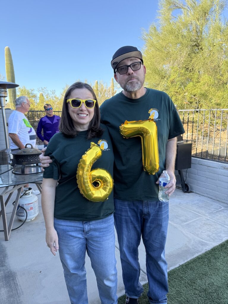 Two adults wearing DIY 6-7 Halloween costumes made with gold Mylar number balloons taped to their shirts.