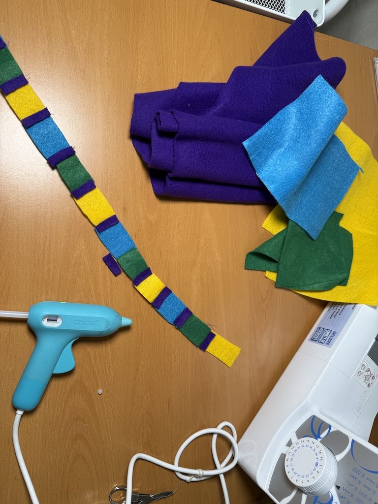 DIY Olivia Octavius headband made with colorful sewn felt pieces and glued purple felt strips.