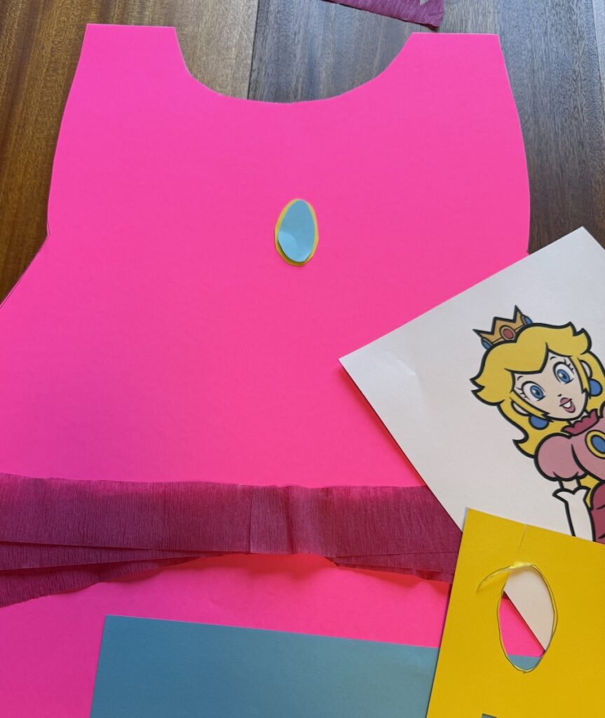 Homemade Princess Peach costume with blue and yellow paper jewel on pink poster board
