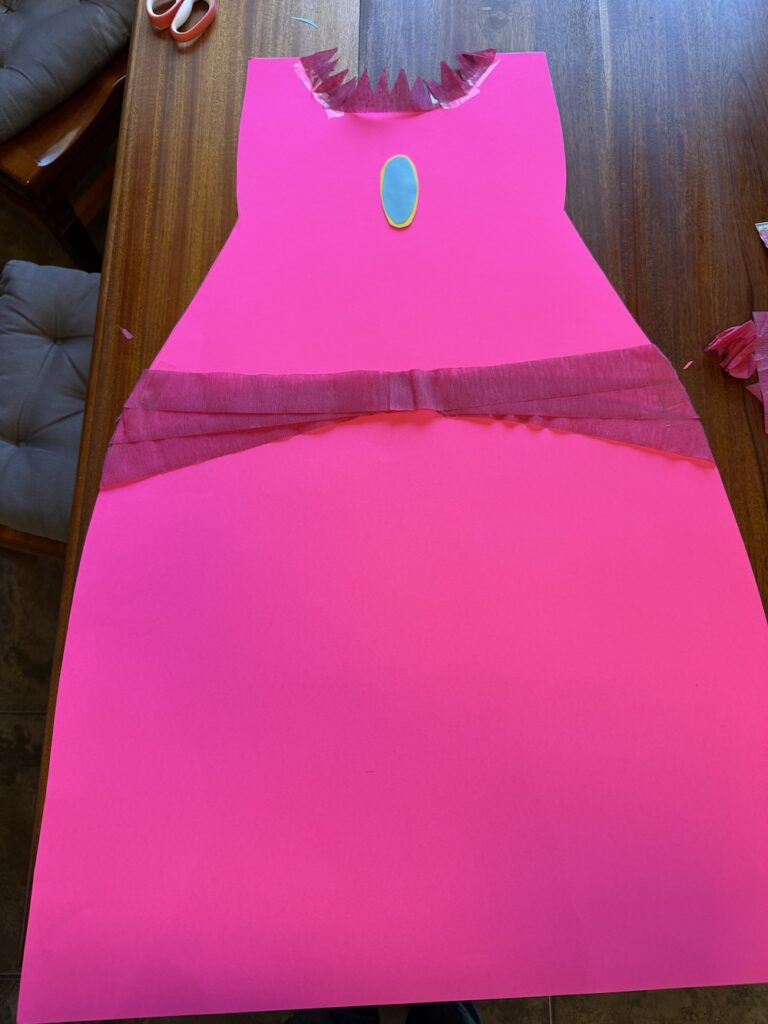 Pink crepe paper decorations attached to a homemade Princess Peach poster board dress